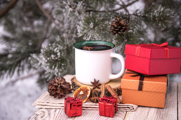 Gift boxes next to a cup of mulled wine on a winter background.