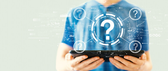 Question marks with young man using a tablet computer