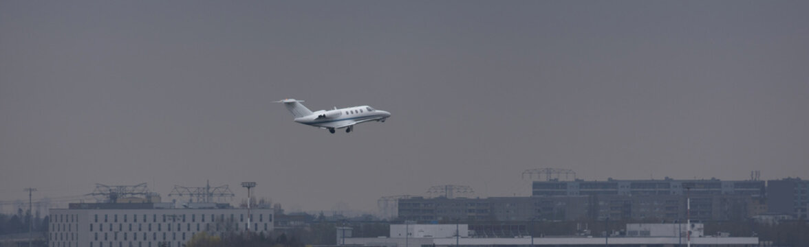 a modern private jet in the air over a city panorama