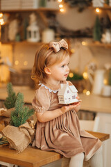 a beautiful little girl in an elegant dress with a toy wooden house. 