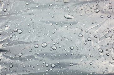 Water flows into drops of various sizes on oilcloth. Raindrops on the surface. Selective focus