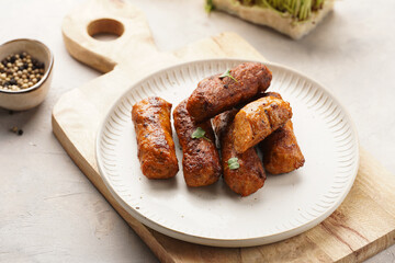 Traditional south european skinless sausages cevapcici made of ground meat and spices on white plate on light wooden board, with thyme and watercress salad