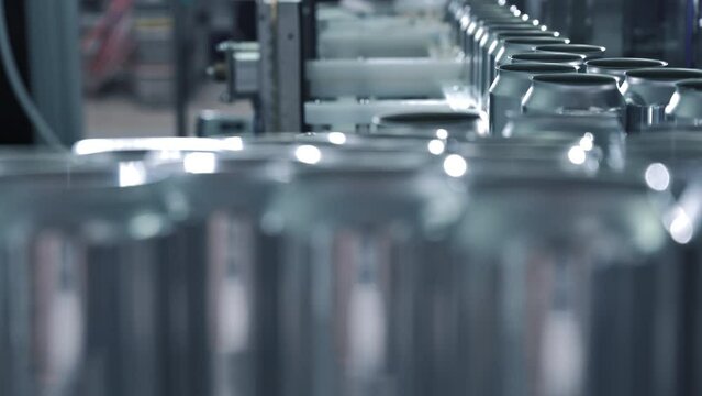 Empty new aluminum cans for drink process are moving in factory line on conveyor belt machine at beverage manufacturing. food and beverage industrial business concept. High quality 4k footage