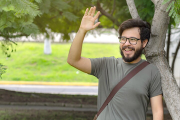 Obraz premium Young mexican man with beard and glasses saying hi in park
