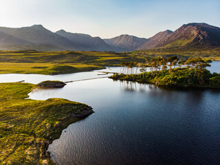 Aerial view of Twelve Pines Island, standing on a gorgeous background formed by the sharp peaks of a mountain range called Twelve Pins or Twelve Bens, Connemara, Ireland