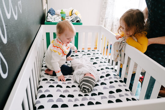 siblings in crib with baby 