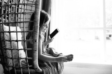 young girl talks on smartphone on wicker chair