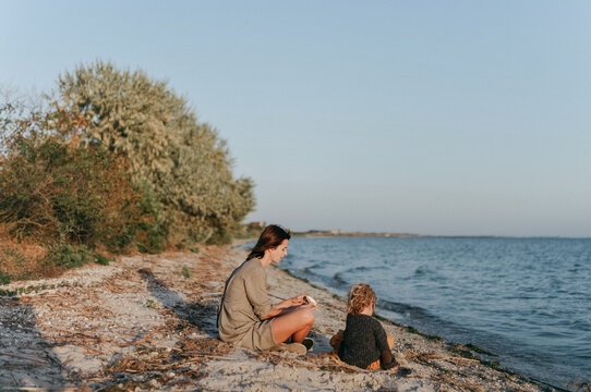 woman and daughter sitting on the sand