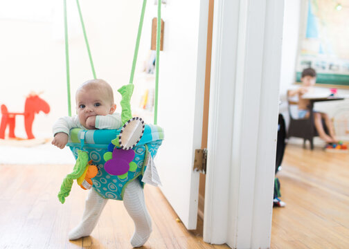 baby in doorway jumper with brother in background