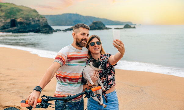 Young couple with their dog taking a selfie on the beach