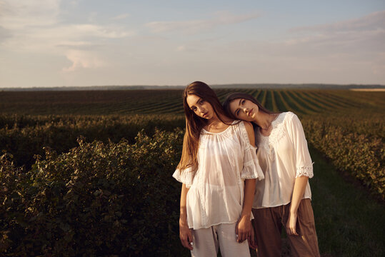 A portrait of two beautiful women models among green field