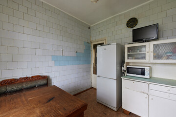 Example of Old Soviet Russian poor interior in Khruschev House. Aged  sideboard, table, chairs. Shabby floor. Tattered wallpaper on the wall. Apartment of pensioners. Selective focus.