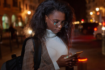 black business woman using smartphone at night, wearing glasses