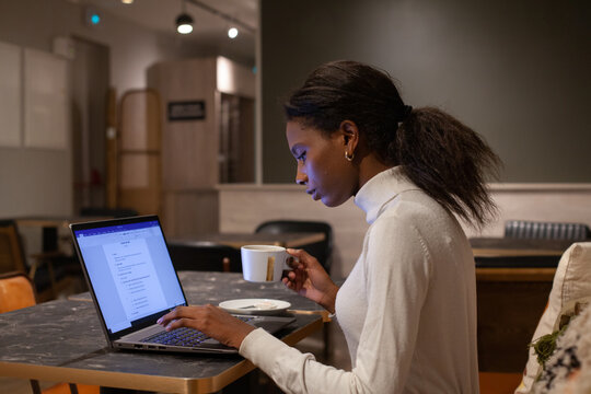 female entrepreneur working with digital documents on laptop in cafe