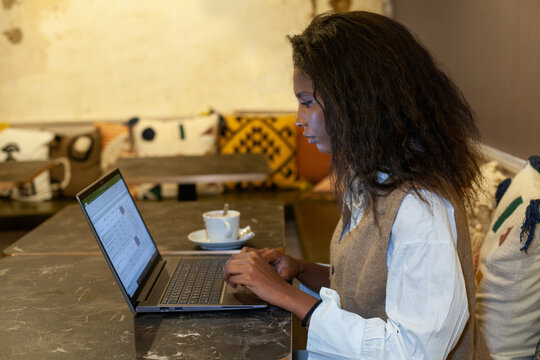 female entrepreneur working with digital documents on laptop in cafe