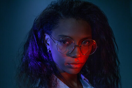 ambitious black woman wearing glasses, studio portrait in neon light 