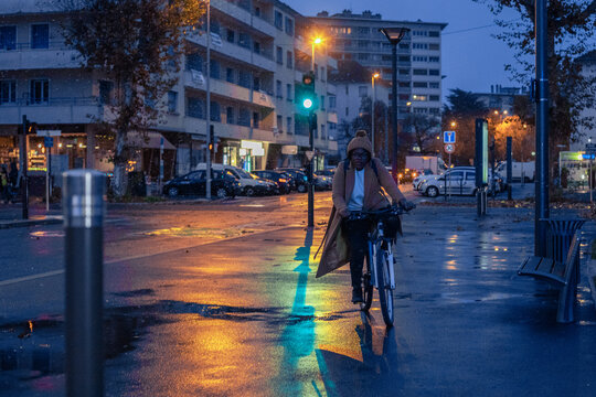 woman riding bike by night, commute by bicycle in snowy cold weather