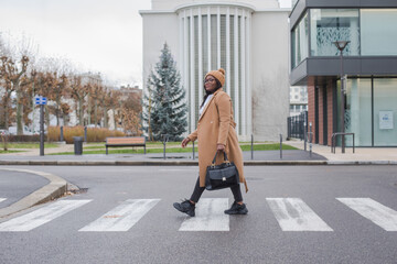 confident black business woman crossing the road, street portrait