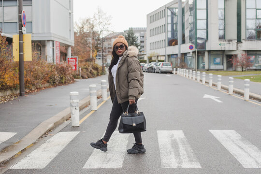 black woman walks in city, full body portrait, crossing the street