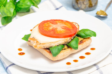 Open-face sandwich with chicken, mozzarella, tomato, pesto and basil on toasted ciabatta, horizontal