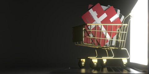 Bank card mockups with flags of Denmark in a small shopping cart on the laptop. 3D rendering