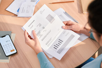 Crop woman reading bills and managing budget