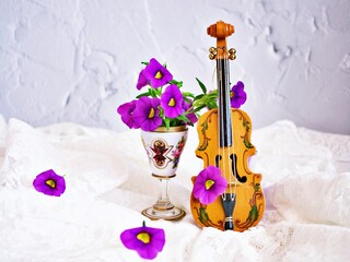 Violet flowers with violin toy on white embroidered cloth for background, Calibrachoa petunia...