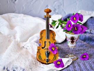 Violet flowers with violin toy on white embroidered cloth for background, Calibrachoa petunia...