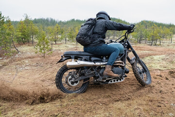 A rider on a classic motorcycle rides in a skid 