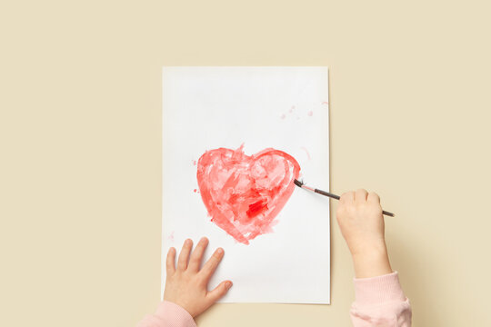 Kid drawing heart on greeting card for mom