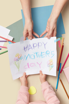 Mother holding paper greeting card painted by child