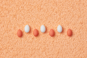 White and orange eggs lying on soft textured background