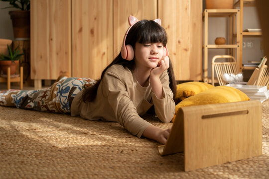 Girl with tablet on support at living room floor