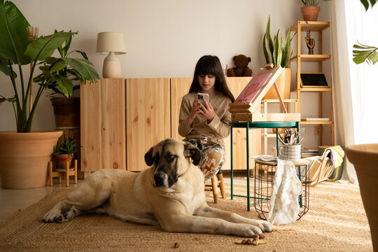 Girl checking smartphone with her big dog at home 