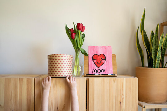 Kid's hand holding gifts on furniture for mother's day