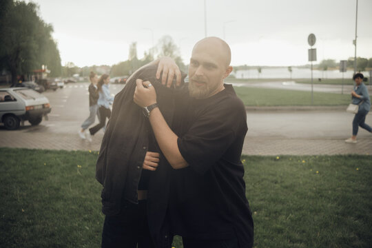 A Couple In Love Is Fleeing The Rain. The Guy Covers The Girl With His Jacket