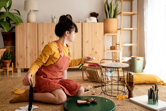 Creative girl making crafts at living room floor