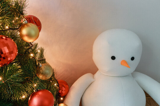 A snowman next to a Christmas tree.