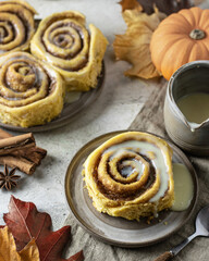 Cinnabon Buns with glaze on a light background with autumn leaves