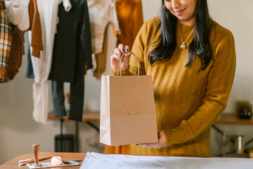 Crop business owner holding paper bag in children's textile store