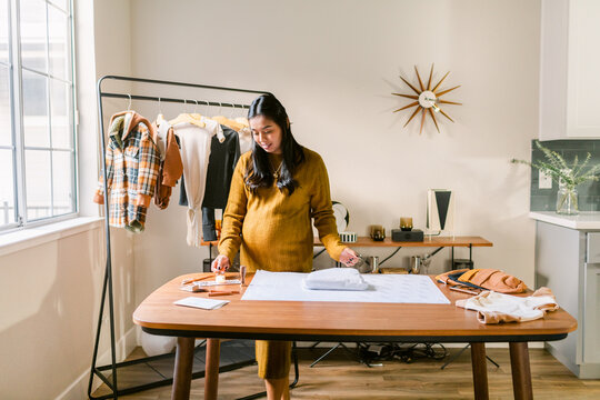 Pregnant designer wrapping children's clothing orders