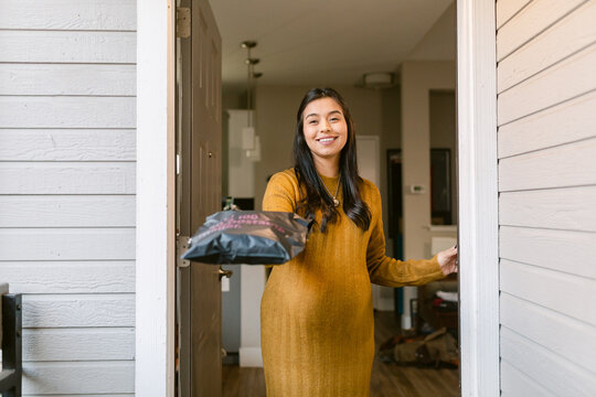 Cheerful pregnant woman delivering package