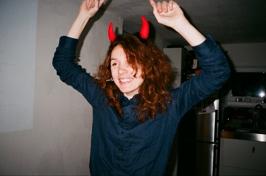 A beautiful smiling woman with a devil horns