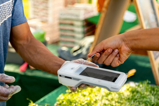 Woman Pays with Card at Outdoor Market with Wireless Payer