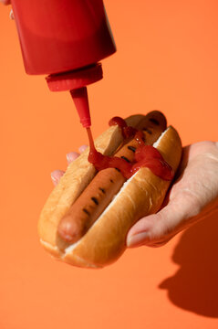 Finger food: putting ketchup on grilled hot dog