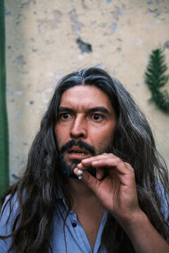 portrait of long-haired man with gray hair and beard smoking