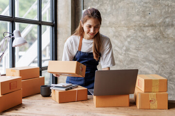 Portrait of Asian young woman SME working with a box at home the workplace.start-up small business owner, small business entrepreneur SME or freelance business online and delivery concept.