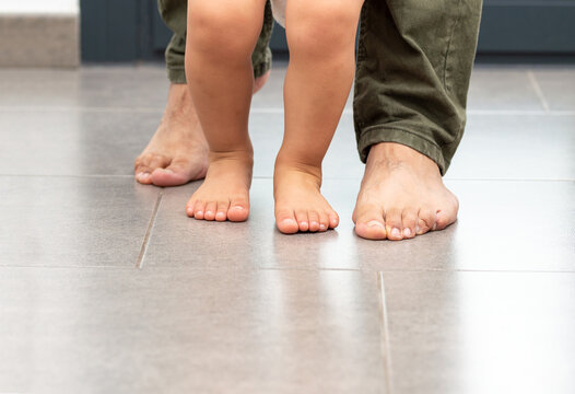 Cropped shot of an unrecognizable little boy learning to walk with his father behind his at home