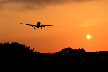 Naklejka na ściany i meble airplane landing at sunset