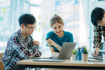 A group of young Asian businessmen brainstorm a new generation of creative young laptop computers. Discuss and exchange ideas for new startup projects together at the meeting.